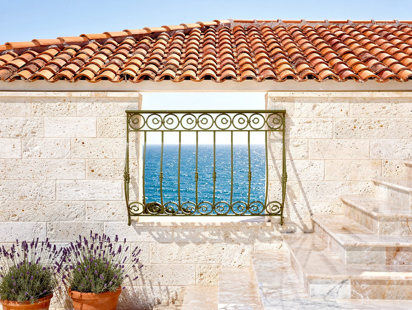 Mediterranean white stone balcony with pink flowers and azure sea